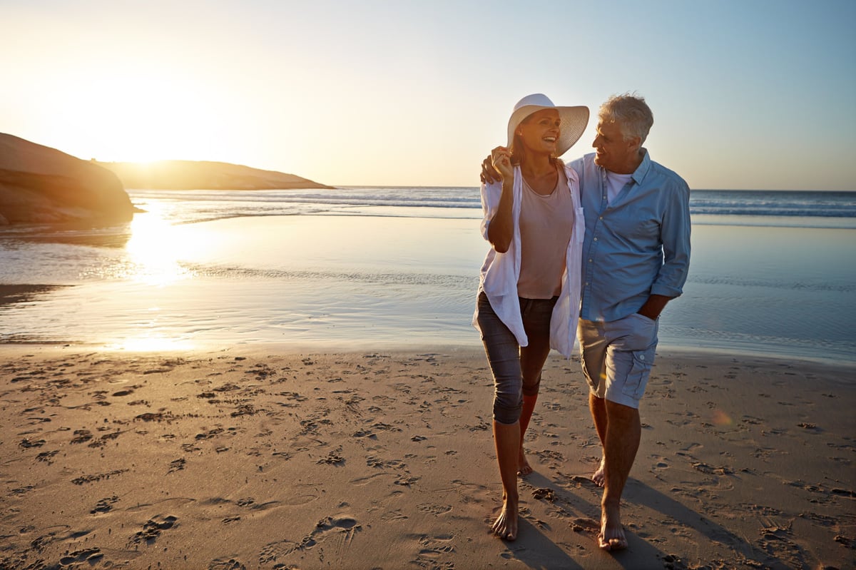 Mature couple spending time together at the beach, walking along the shore
